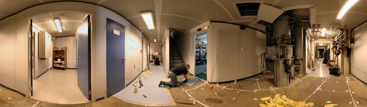 [PanoMondo.jpg]
Jean and Stef applying the 'Mondo' tiles to the 1st floor of the noisy building. The door on the left leads to the incinolet toilets and the washing machines, the corridor behind Stef leads to the backup generator and the power plant and the corridor on the right leads to the quiet building. The stairs lead up to the gym, food storage and restaurant. Right of the stairs is the station leader office. And farther right is one of the mighty hydraulic feet of the station.