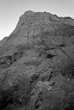 [ScenicCruise.jpg]
View of the Scenic Cruise from near the base in early morning. Starts in the crack on the left, behind the tree, continues up the large right-facing dihedral, then avoids the Layton Kor offwidth by taking the next crack to the right and merges back with it higher.