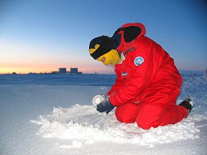 Emanuele filling a bottle with snow while the sun is getting close to returning